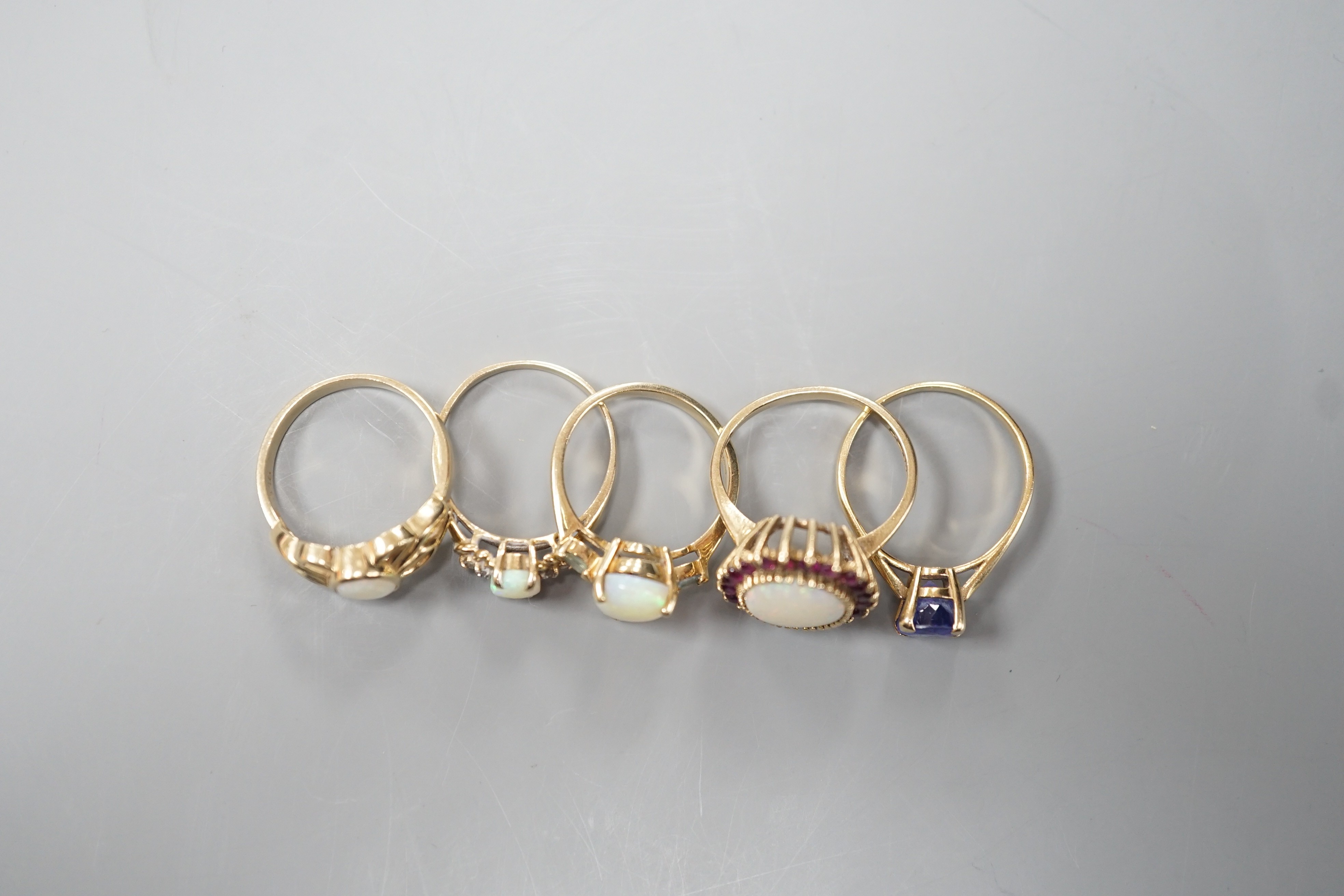 Five assorted modern 9ct gold and gem set dress rings, including white opal and garnet oval cluster, white opal and diamond chip and single stone white opal